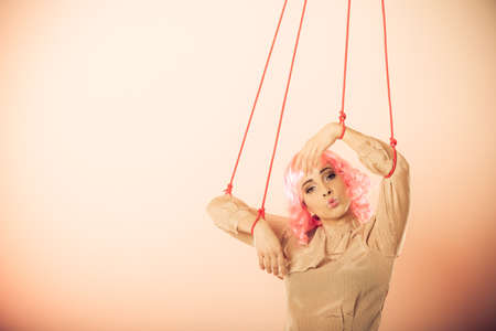Young woman girl stylized like marionette puppet on stringの写真素材