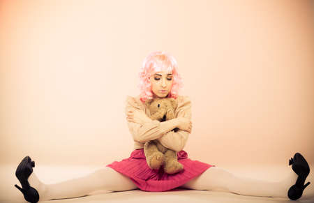 Mental disorder concept. Young childlike woman wearing like puppet doll holding teddy bear toy...