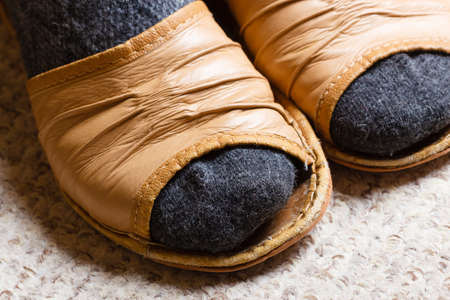 Cozy, comfortable, soft footwear. Female feet with socks in slippers at homeの写真素材