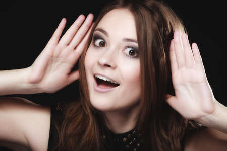 Gossip scandal or secrets. Young woman teen girl with hands to ear listening on blackの写真素材