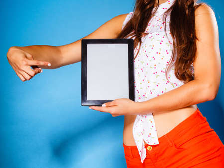Woman teen girl showing blank copy space screen of tablet touchpad computer on blue. Electronic technology.の写真素材