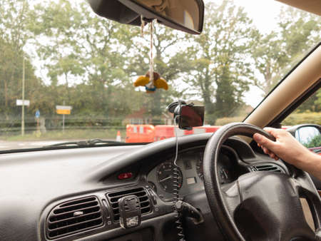 Male driver hand holding steering wheel of a car on english roadの写真素材