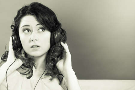 Young people leisure relax concept. Closeup teen cute girl in big headphones listening music mp3 relaxing black and white photoの写真素材