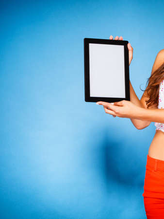 Woman teen girl showing blank copy space screen of tablet touchpad computer on blue. Electronic technology.の写真素材