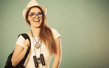Summer vacation and tourism concept. Smiling woman in straw hat with backpack binocular compass on blue portraitの写真素材