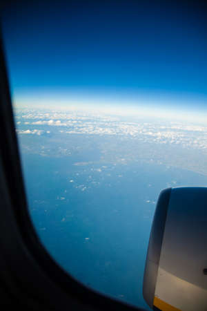 Blue white cloudy sky and engine. View from window of airplane flying in clouds. Skyscape...