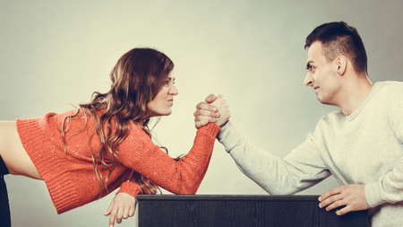 Partnership relationship concept. Girlfriend confronts his boyfriend. Woman and man arm wrestling...