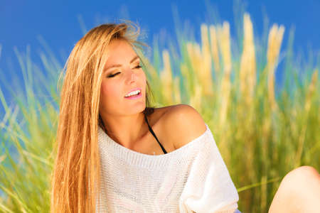 Young woman female model posing outdoor on background of dunes sky and grassの写真素材