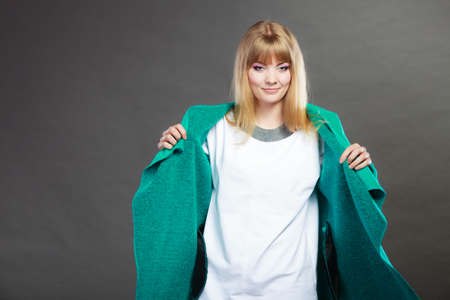 Fashion. Blonde girl fashionable woman trying blue coat dark backgroundの写真素材