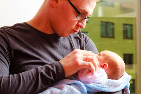 Parenting concept. Father holding delicate his newborn baby girl, at homeの写真素材