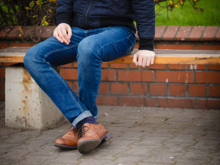 Autumn fashion, foot wear. Male legs in jeans and boots striped socks outdoor on streetの写真素材