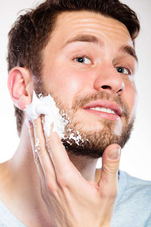 Health beauty and skin care concept. Closeup young bearded man with foam on face preparing to shave, guy shavingの写真素材