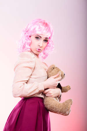 Mental disorder concept. Young childlike woman wearing like puppet doll holding teddy bear toy studio shotの写真素材
