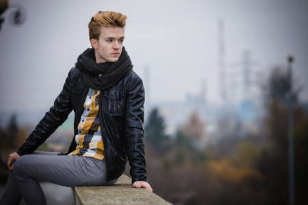 Street fashion. Young fashionable man guy with stylish hair posing outdoor on cityspace backgroundの写真素材