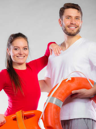Accident prevention and water rescue. Young man and woman lifeguard couple on duty holding ring buoy float lifesaver equipment on grayの写真素材