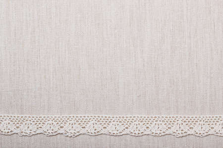 Lace ribbon on natural linen, bright cloth fabric background. Border frameの写真素材
