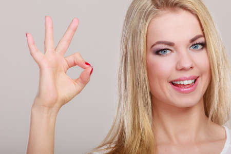 Happiness concept. Happy woman showing ok hand sign gesture on gray backgroundの写真素材