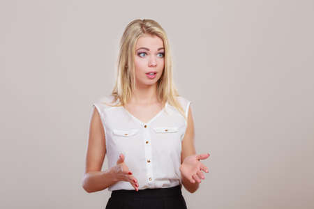 Shrugging woman in doubt doing shrug, attractive confused girl gesturing do not know sign on gray...