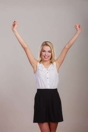Blonde girl spreading hands with joy, happy successful young woman with arms up. Success positive emotions.の写真素材