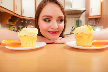 Woman looking at delicious cake with sweet cream and fruits on top. Appetite and gluttony concept.