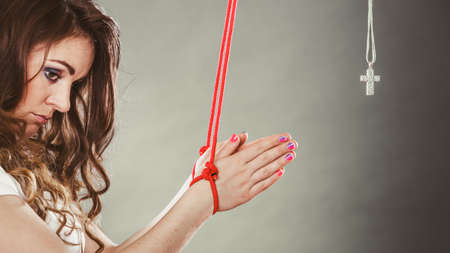 Tied woman forced to pray. Fake faith belief concept. Christian religion. Girl praying to god because of society pressure.の写真素材