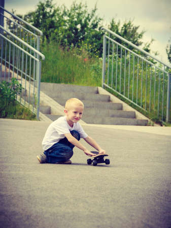 Sporty child with his skateboard outdoor. Active boy skateboarding on pavement sidewalk. Kid practicing outside.の写真素材