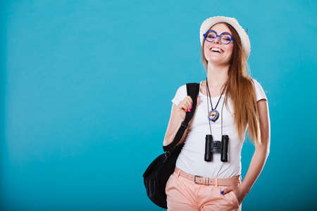 Summer vacation and tourism concept. Smiling woman in straw hat with backpack binocular compass on blue portraitの写真素材