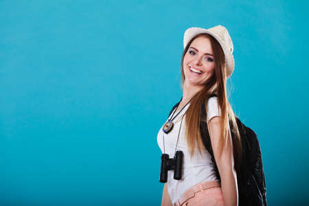 Summer vacation and tourism concept. Smiling woman in straw hat with backpack binocular on blue...