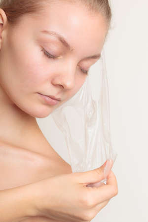Beauty skin care cosmetics and health concept. Closeup young woman face, girl removing facial peel off mask on gray. Peelingの写真素材
