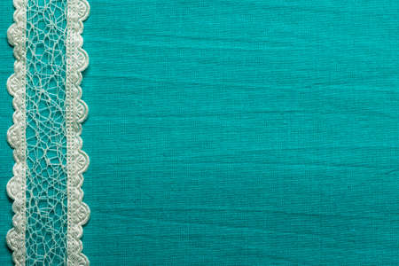 Retro border for invitations celebration. Vintage white lace over green blue textile background.の写真素材