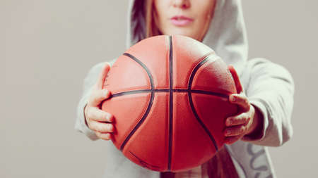 Sporty teenager girl wearing hooded sweatshirt holding basketball. Teen sport.の写真素材
