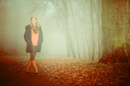 Woman walking relaxing in foggy day in romantic autumn forest park outdoor, tinted aged photoの写真素材