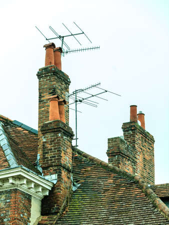 Roof tops and brick chimneys on house in typical english townの写真素材