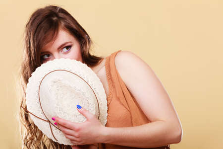 Summer holidays and vacation. Attractive girl holds summer straw hat covering her face having funの写真素材