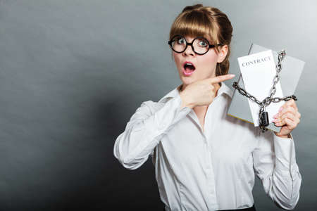 Business concept, limited by contract. Woman holding in hands paper document chained with padlockの写真素材