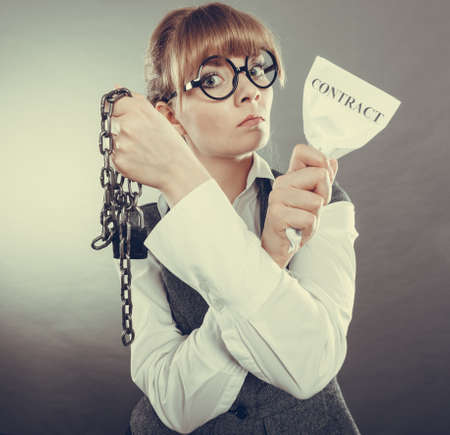 Businesswoman woman ending agreement deal. Young girl holding chain breaking free creasing squeezing paper. Termination, breach of contract.
の写真素材