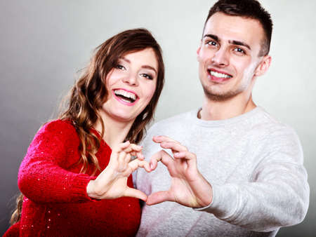 Love concept. Closeup Smiling woman and man forming heart shape with their fingers hands