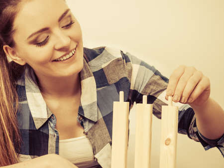 woman assembling wooden furniture using screwdriver. diy enthusiast. young girl doing home...
