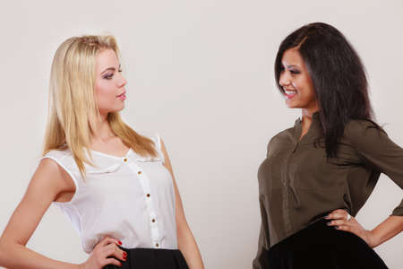 Two young fashionable women caucasian and african posing studio portrait on gray