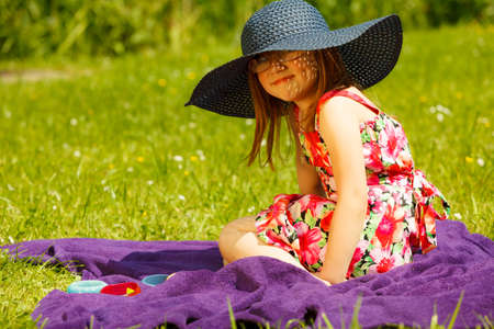 Cute little girl wearing big summer hat pretending to be woman lady. Child imitate mother playing in park, outdoorsの写真素材