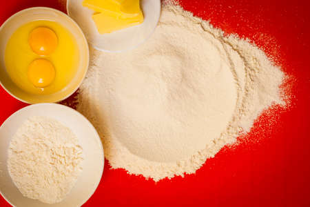 Cooking concept. Preparation for baking, bake ingredients and kitchen tools to make a cake on red...