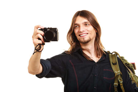 Man tourist backpacker on trip taking photo picture with camera. Young guy hiker backpacking. Summer vacation travel. Isolated on white background.の写真素材