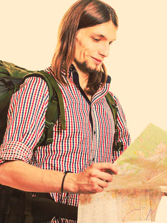 Man tourist backpacker reading map on trip. Young guy hiker searching looking for direction guide....