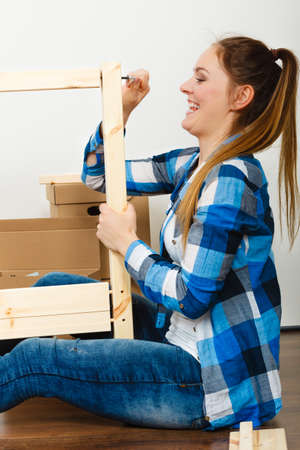Woman assembling wooden furniture using hex key. DIY enthusiast. Young girl doing home improvement.の写真素材