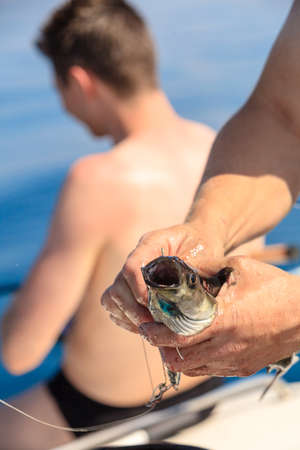 Fishing bait - rod with wobbler, fisherman angler holding fish