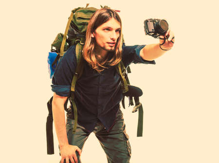Man tourist backpacker on trip taking photo picture with camera. Young guy hiker backpacking. Summer vacation travel.   の写真素材