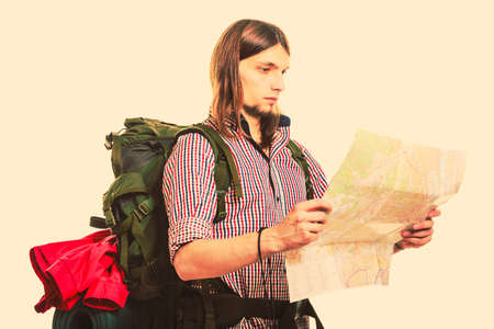 Man tourist backpacker reading map on trip. Young guy hiker searching looking for direction guide. Male backpacking. Summer vacation travel.  の写真素材