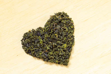 Diet healthcare concept. Green tea heart shaped on wooden surface. Healthy food drink for lower heart disease riskの写真素材