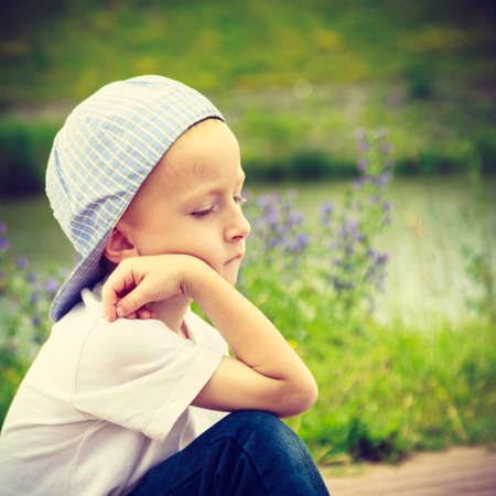 Pensive boy child thinking and daydreaming. Thoughtful kid leaning on his hand looking forward. Imagination.の写真素材