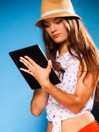 Technology internet modern lifestyle concept. Young summer girl using tablet computer reading. Latin female with e-book reader touchpad pc.の写真素材